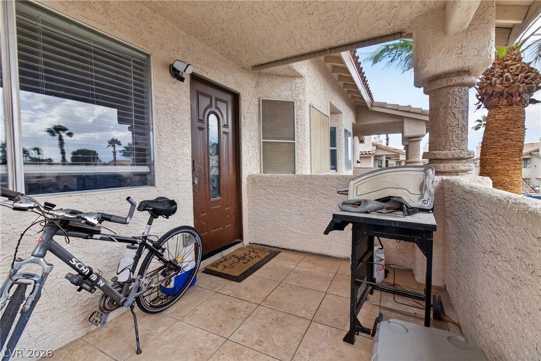 1341 Pinto Rock Lane, #202, Las Vegas, NV 89128 A covered tiled patio features a private stucco entryway and support columns.