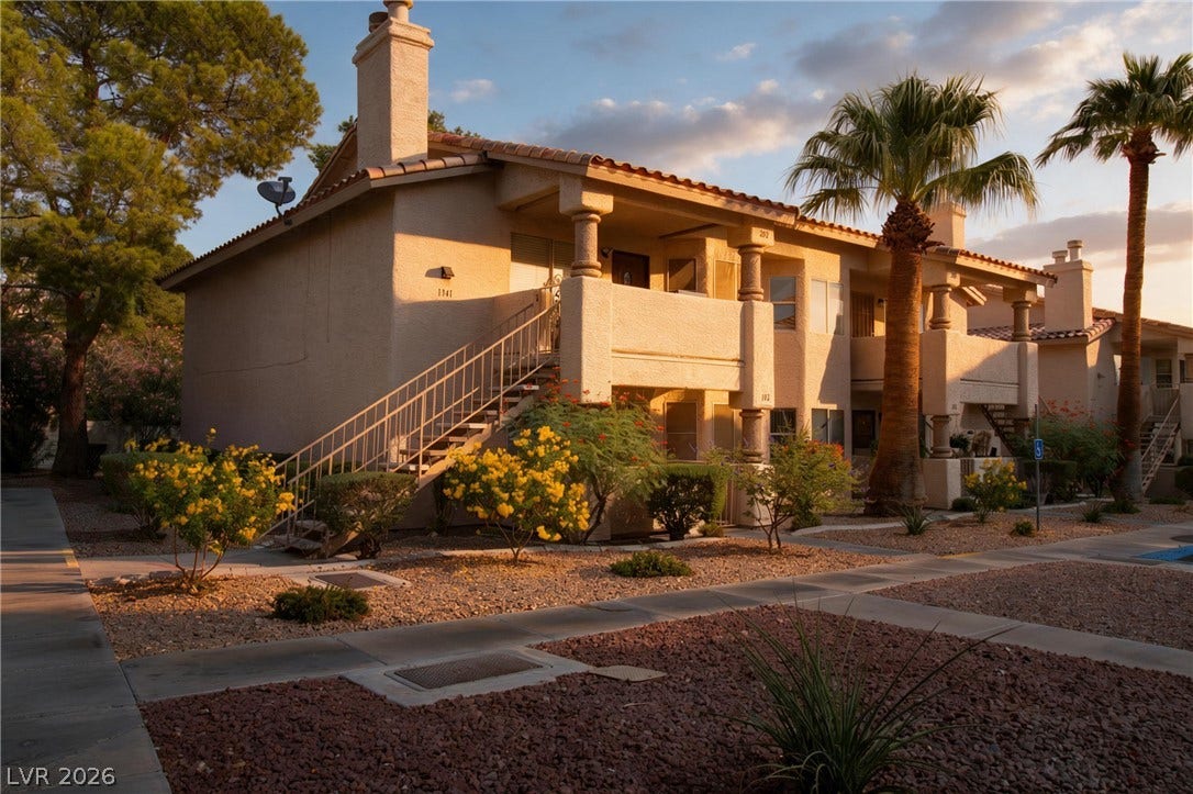 1341 Pinto Rock Lane, #202, Las Vegas, NV 89128 Warm desert sunlight illuminates this multi-level stucco exterior featuring integrated balconies and tiled rooflines.
