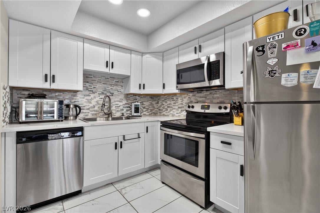 1341 Pinto Rock Lane, #202, Las Vegas, NV 89128 Crisp white cabinetry paired with modern stainless steel appliances defines this kitchen space.