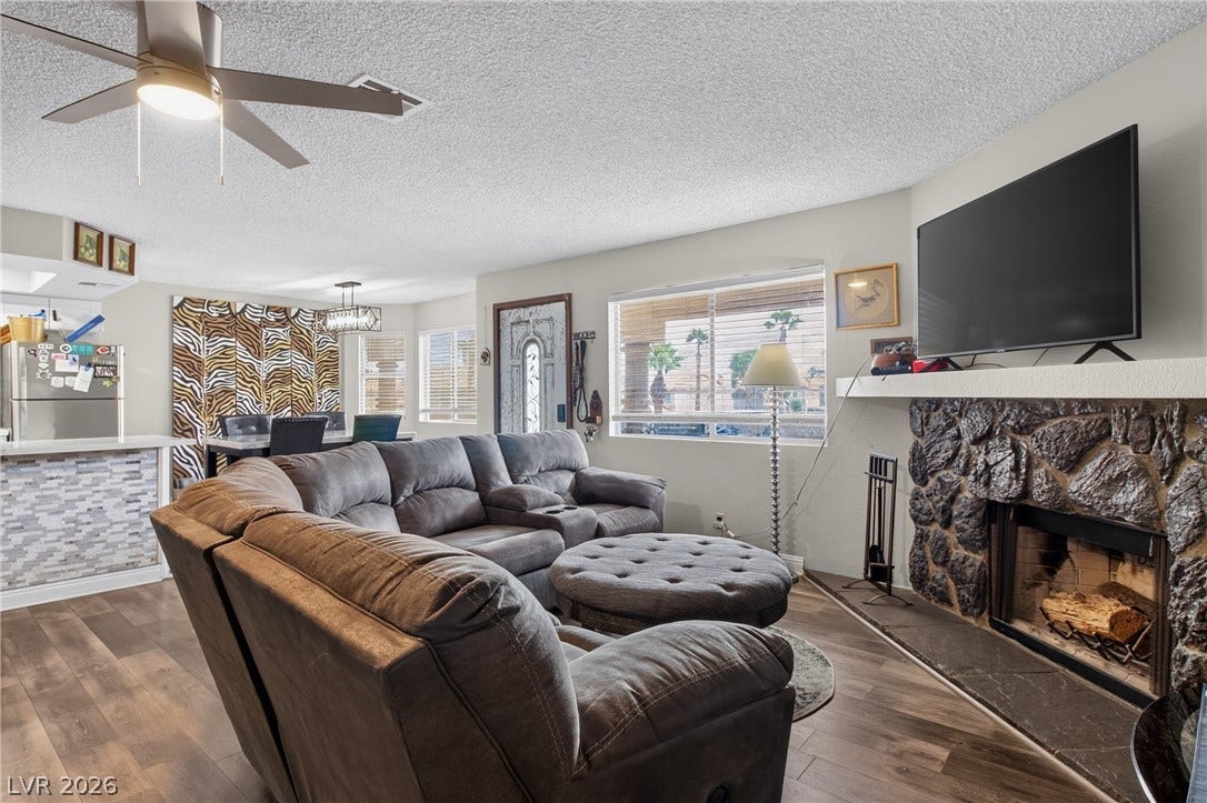 1341 Pinto Rock Lane, #202, Las Vegas, NV 89128 Rich wood-look flooring and a rugged stone fireplace anchor this welcoming open-concept living space.