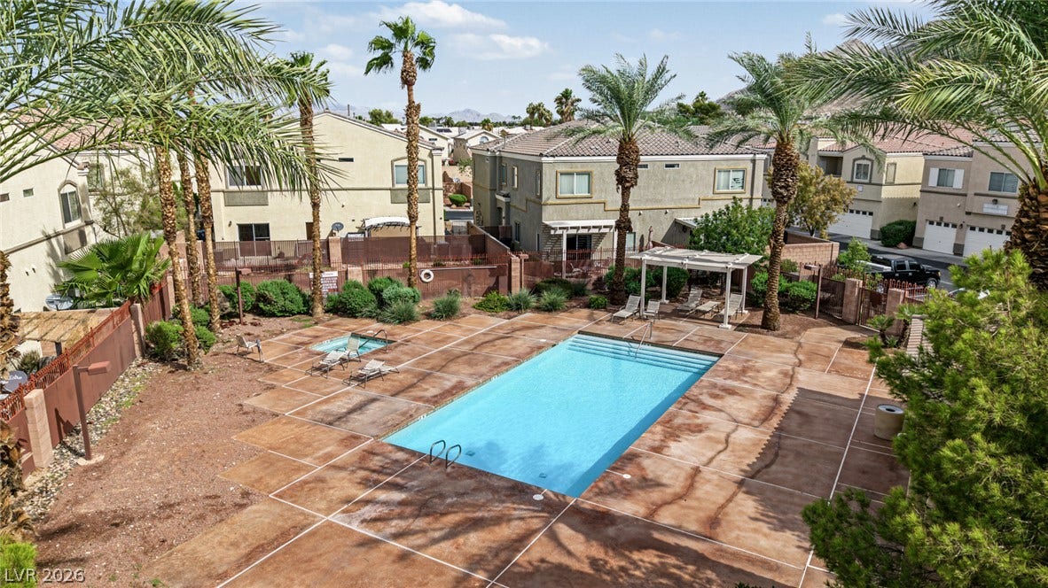 Lush palm trees frame a sparkling community swimming pool and spa area surrounded by residences.
