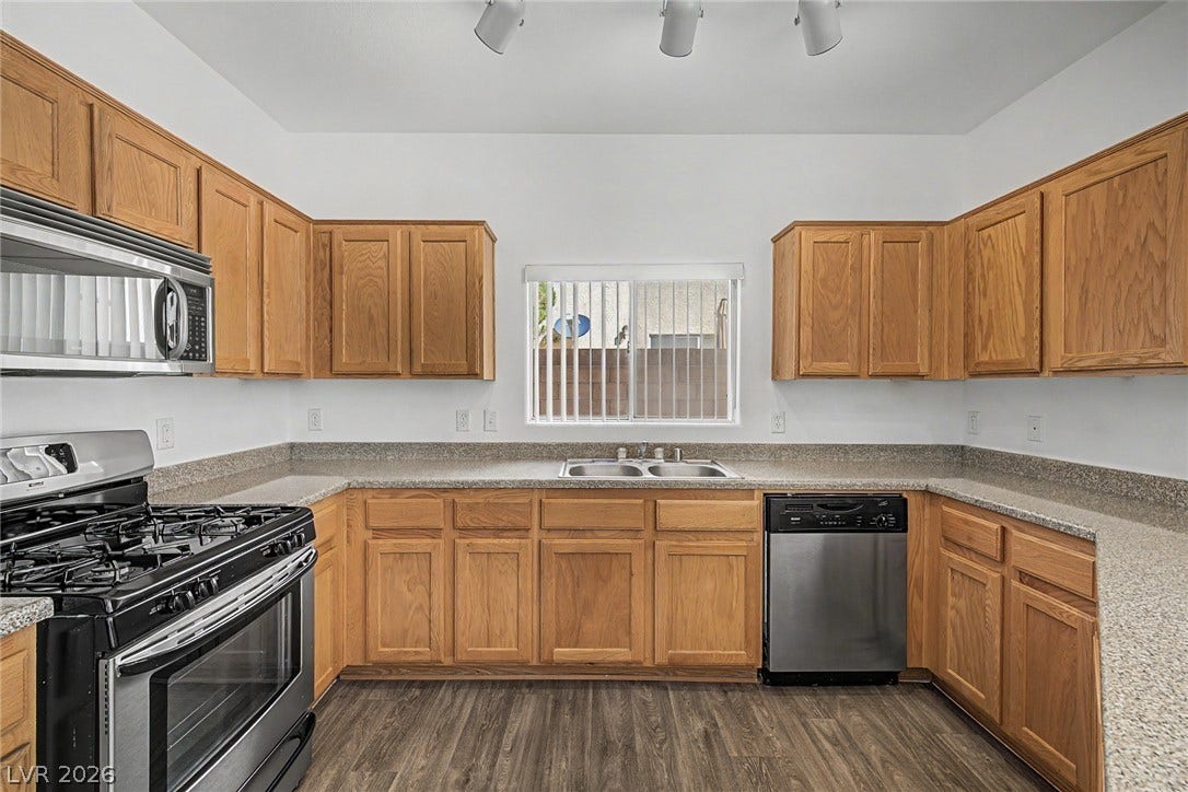 Warm oak cabinetry pairs with speckled countertops and durable wood-look flooring.