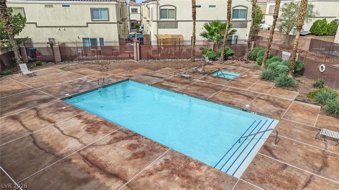 A fenced community pool area features a built-in spa and concrete decking.