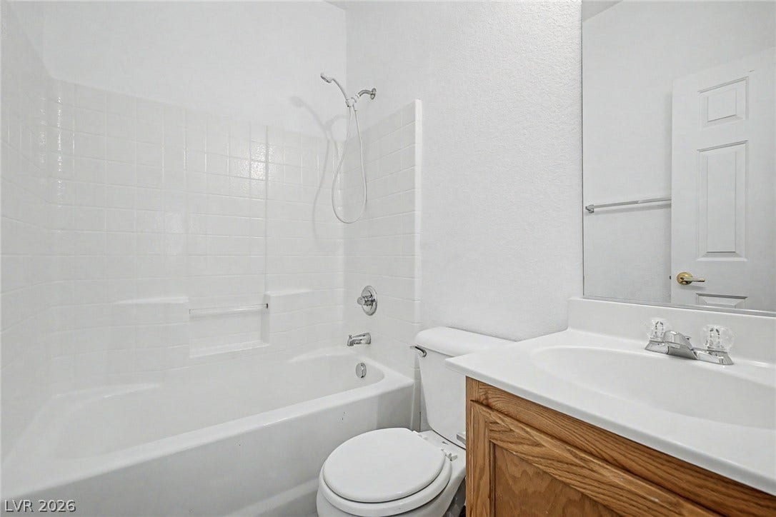 A classic bathtub and wooden vanity define this functional bathroom layout.