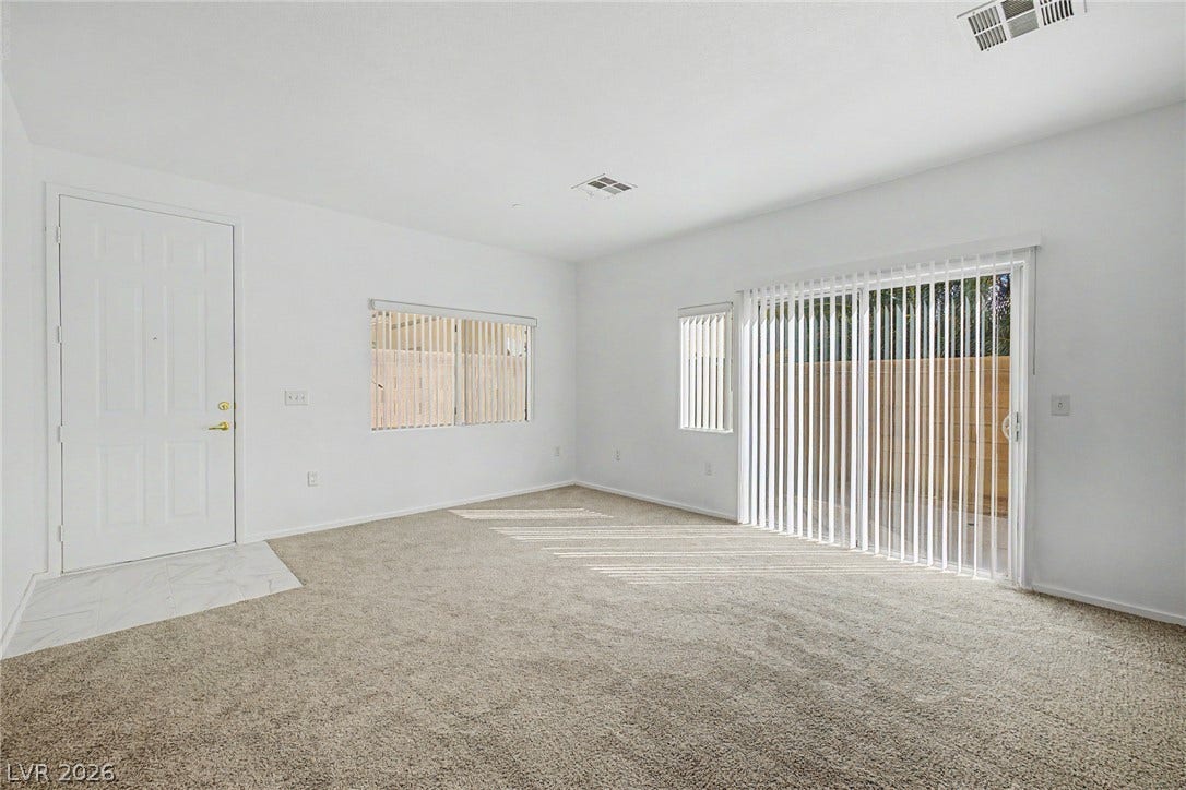 Natural light streams through sliding glass doors into a versatile living space with wall-to-wall carpeting.