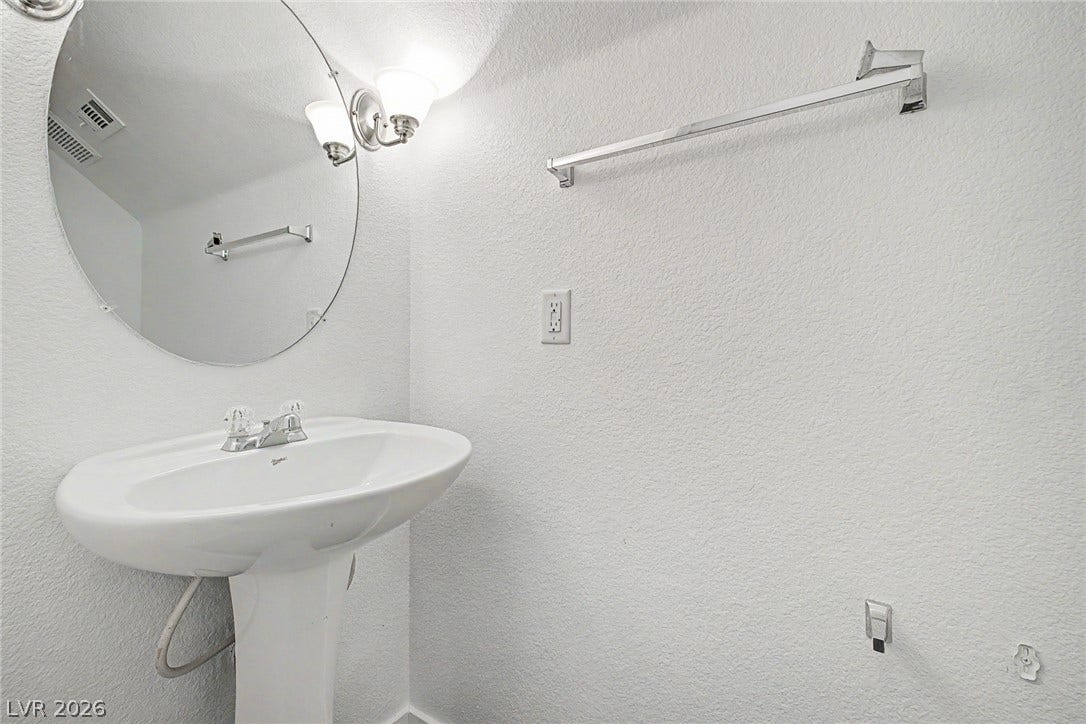 A classic pedestal sink sits beneath a round mirror in this compact powder room.