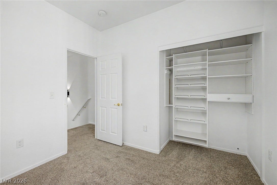 An organized closet system anchors this carpeted secondary bedroom with a nearby stairway transition.