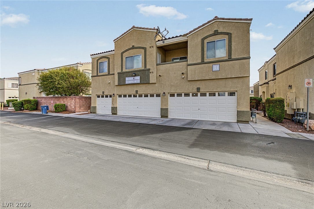 Multi-level stucco exterior showcases a structured layout featuring integrated garage parking bays.