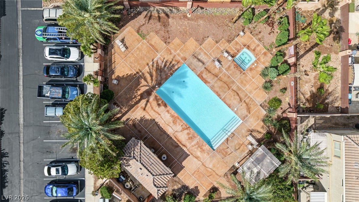 An aerial view showcases a sparkling swimming pool surrounded by a spacious concrete patio.
