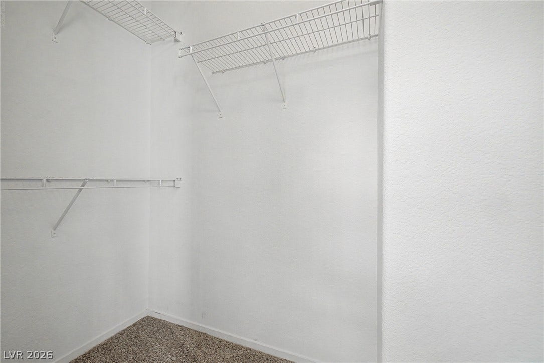 Ample wire shelving and soft carpeting define this functional walk-in closet space.