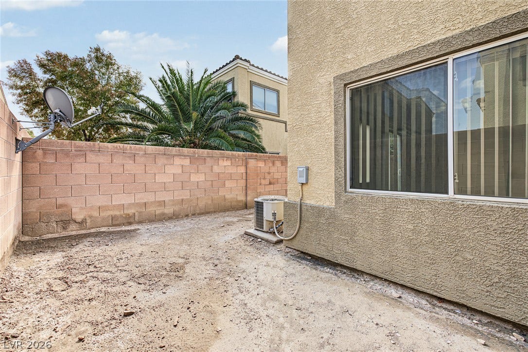 A stucco exterior frames the private outdoor space bordered by a block wall.