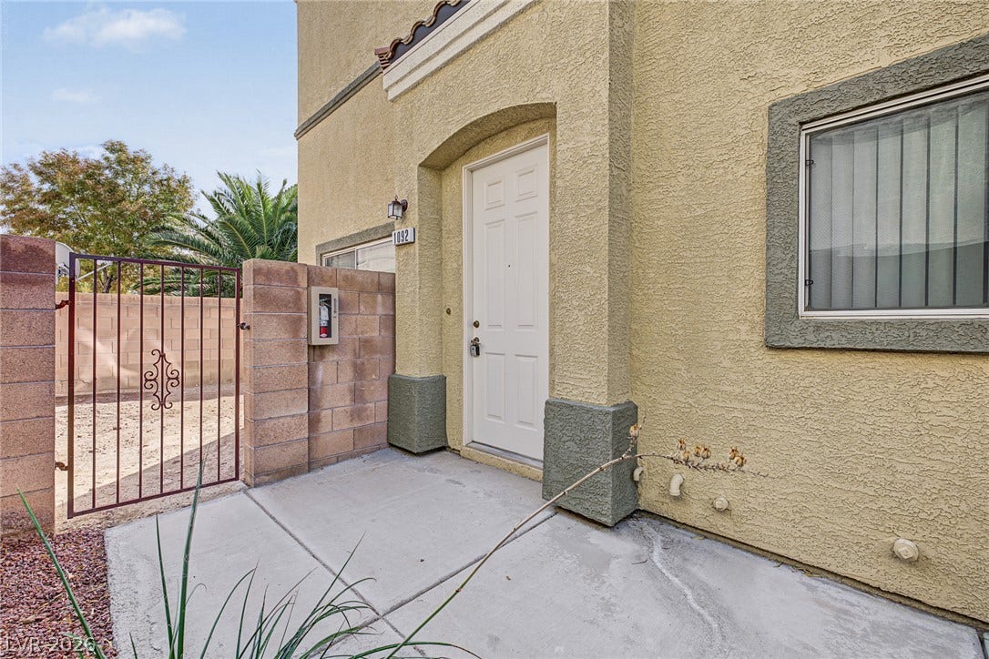 An inviting stucco entryway features a solid front door alongside a secure gated side patio.
