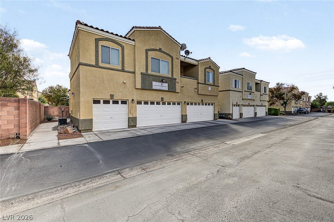 Multi-level townhouse units feature attached garages beneath private balconies under a tile roof.