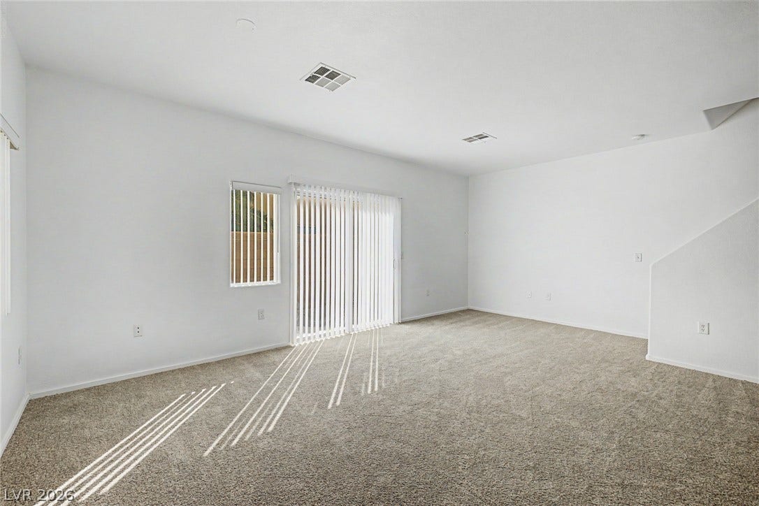 Plentiful natural light streams across the carpeted flooring of this versatile living space.
