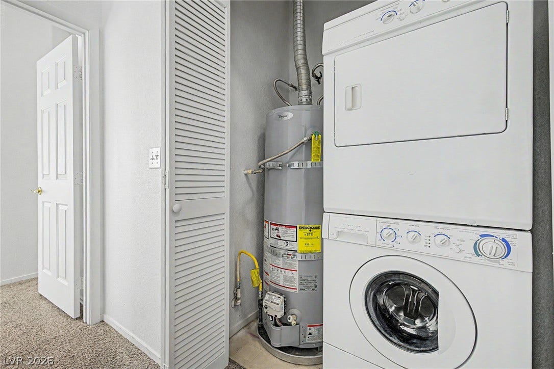 An efficient utility closet features a stacked washer and dryer setup next to the water heater.