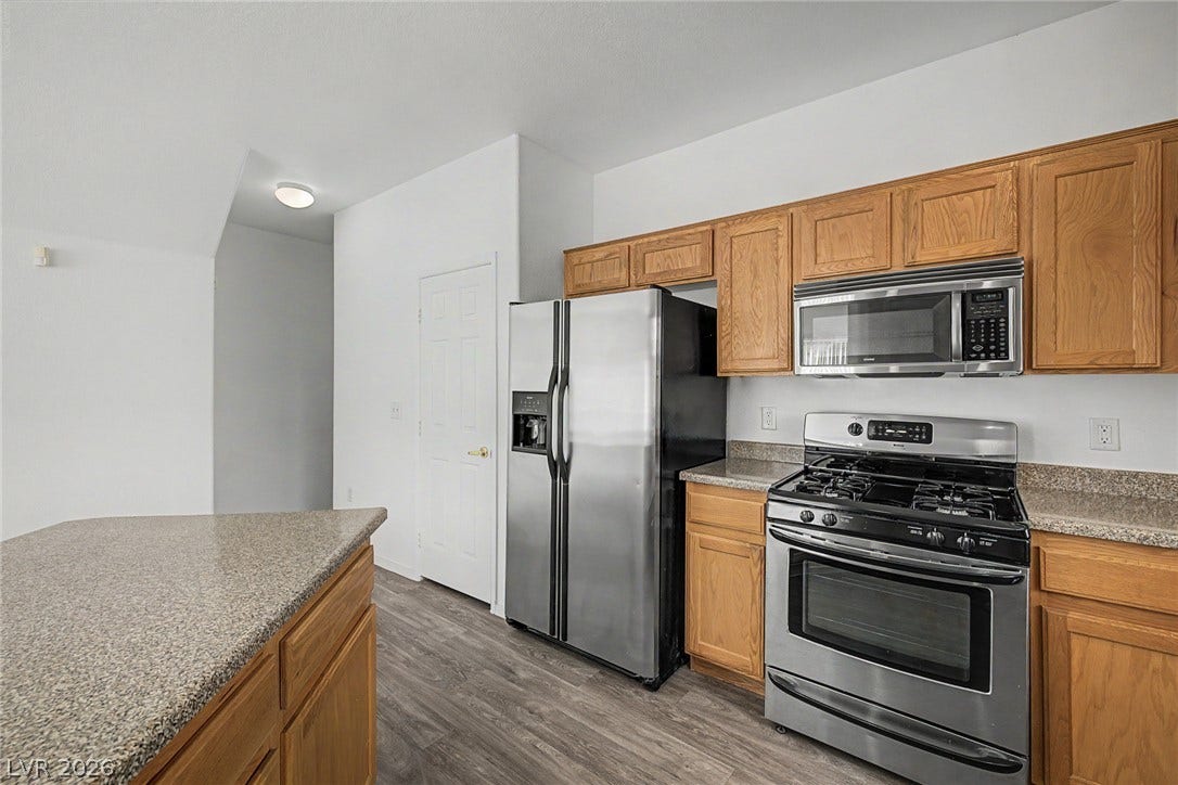Oak cabinetry paired with granite-look countertops and stainless steel appliances creates an efficient cooking workspace.