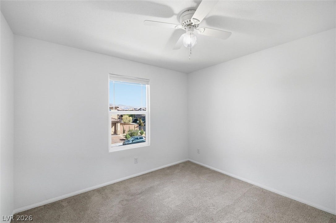 6047 Castle Gardens Avenue, Las Vegas, NV 89130 Crisp neutral walls frame a comfortable bedroom featuring plush carpet and a neighborhood view.