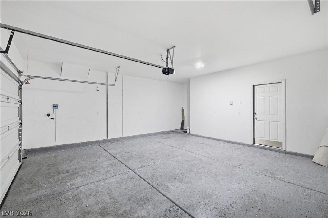 6047 Castle Gardens Avenue, Las Vegas, NV 89130 A spacious garage features durable concrete flooring and an automatic overhead door system.