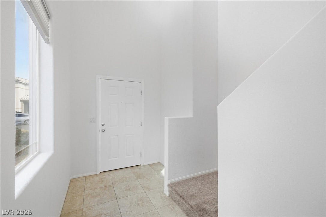 6047 Castle Gardens Avenue, Las Vegas, NV 89130 Clean lines and soaring ceilings define this airy entryway with adjacent carpeted stairs.