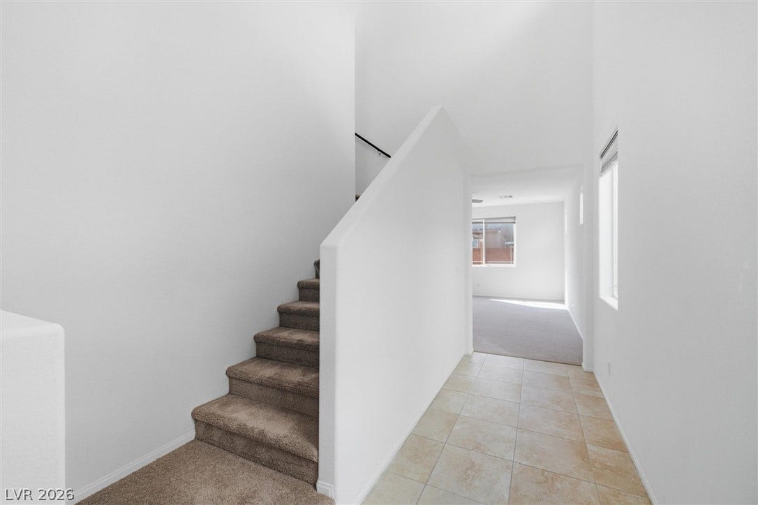 6047 Castle Gardens Avenue, Las Vegas, NV 89130 Tiled flooring and carpeted stairs define the bright entrance hallway of this multi-level home.