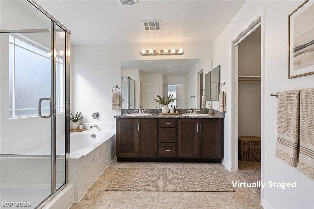 6047 Castle Gardens Avenue, Las Vegas, NV 89130 Double vanity sinks and a separate soaking tub create a functional primary bath layout.