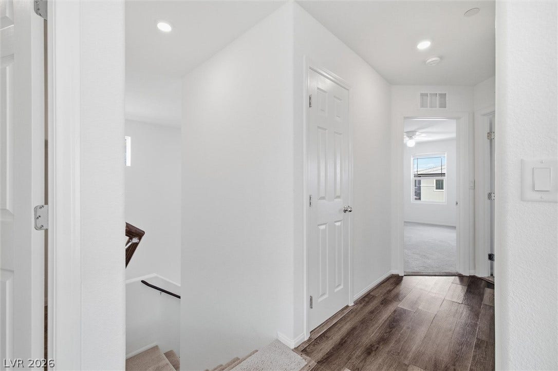 6047 Castle Gardens Avenue, Las Vegas, NV 89130 Rich wood-inspired flooring anchors a light-filled upper hallway connecting key living spaces.