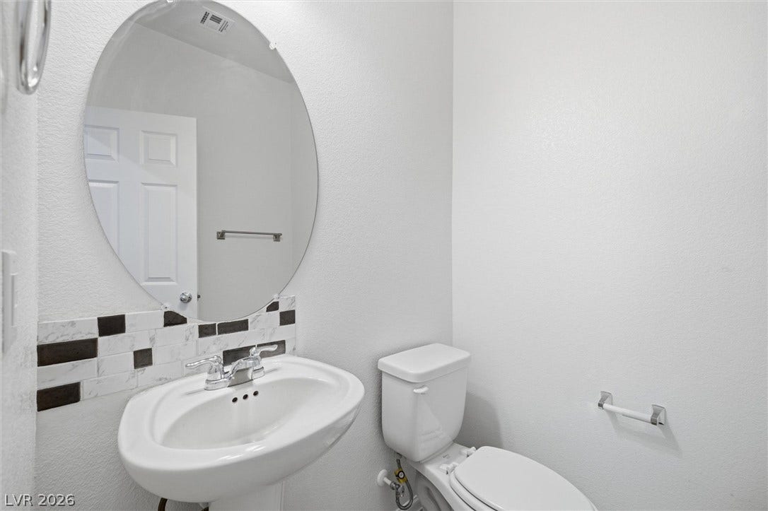 6047 Castle Gardens Avenue, Las Vegas, NV 89130 A crisp powder room features a pedestal sink paired with a sleek oval mirror.