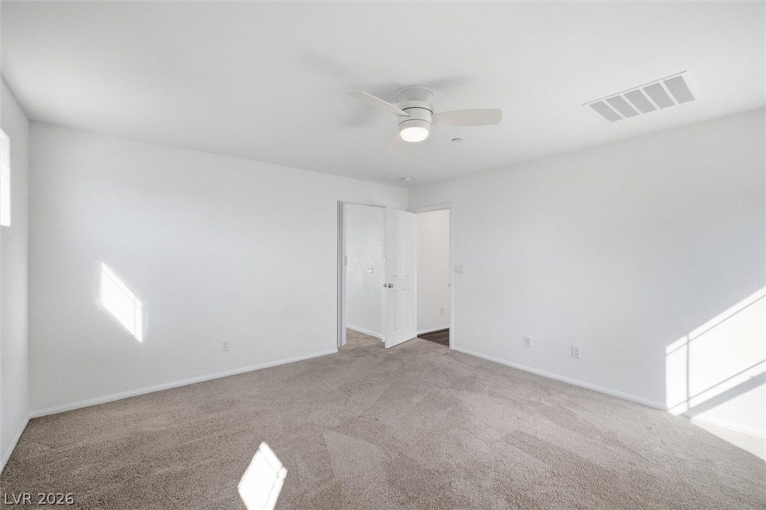 6047 Castle Gardens Avenue, Las Vegas, NV 89130 Plush carpeting anchors this bright bedroom beneath crisp white walls.