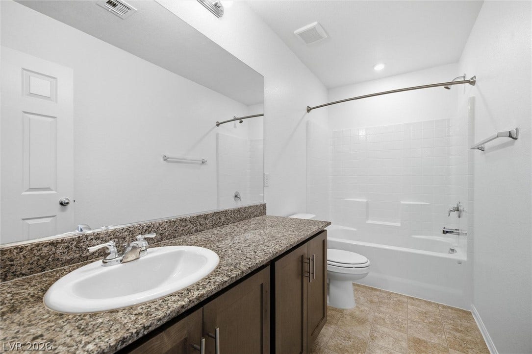 6047 Castle Gardens Avenue, Las Vegas, NV 89130 Polished stone counters and clean tile flooring define this functional bathroom space.