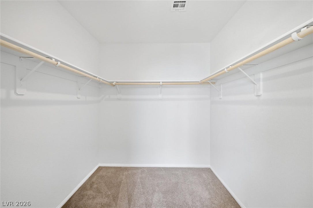 6047 Castle Gardens Avenue, Las Vegas, NV 89130 Ample hanging rods and built-in shelving maximize storage space in this carpeted walk-in closet.