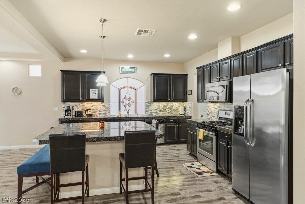 8430 Golden Amber Street, Las Vegas, NV 89139 A spacious kitchen features dark cabinetry, stone countertops, and a central island.