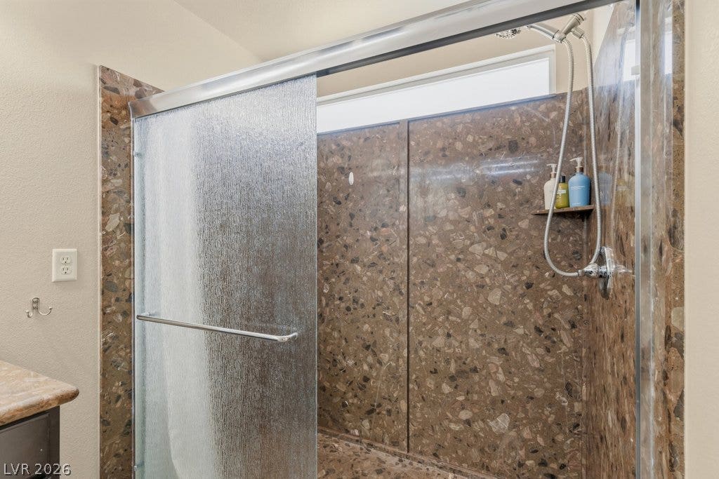 8430 Golden Amber Street, Las Vegas, NV 89139 Natural stone textures pair with textured glass slider panels in this modern shower enclosure.