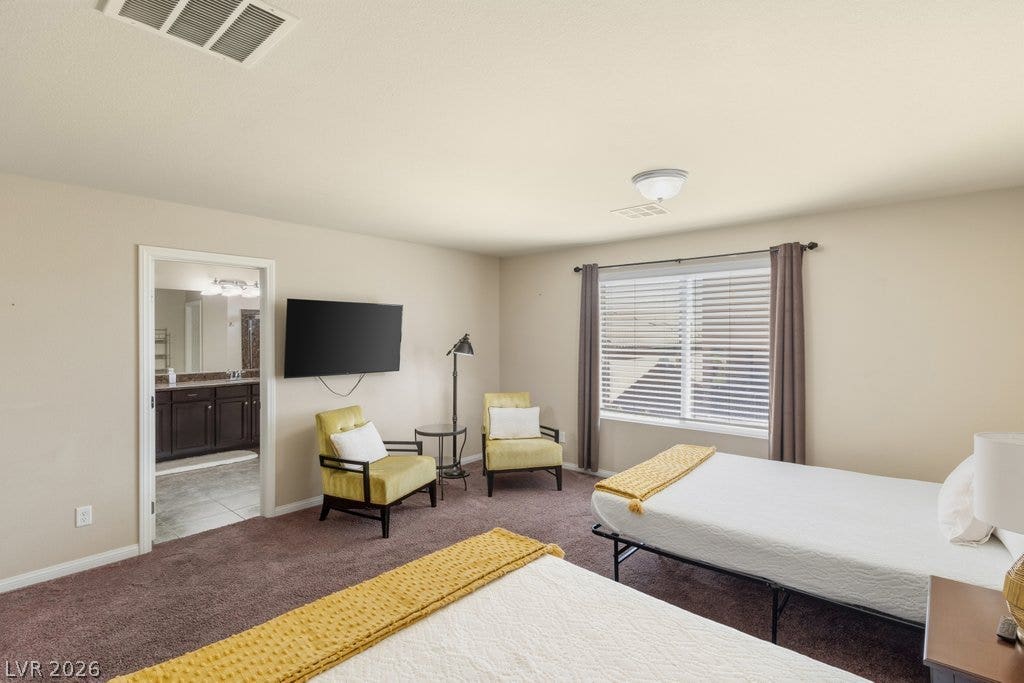 8430 Golden Amber Street, Las Vegas, NV 89139 A spacious bedroom features soft carpeting and direct access to an en suite bathroom.