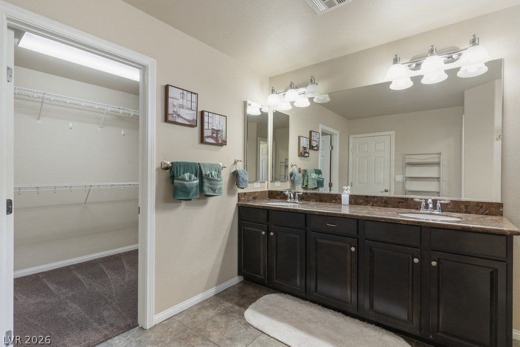 8430 Golden Amber Street, Las Vegas, NV 89139 Granite counters and dark cabinetry define this spacious bathroom featuring access to a walk-in closet.