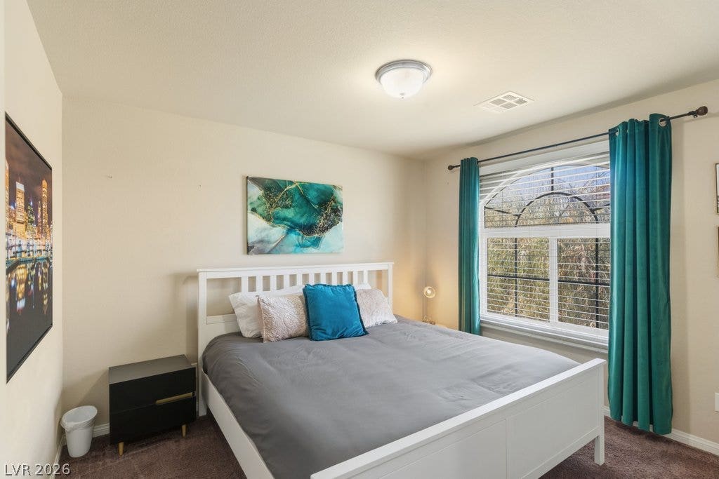 8430 Golden Amber Street, Las Vegas, NV 89139 Natural light pours through a large arched window into this comfortable bedroom with soft carpeting.