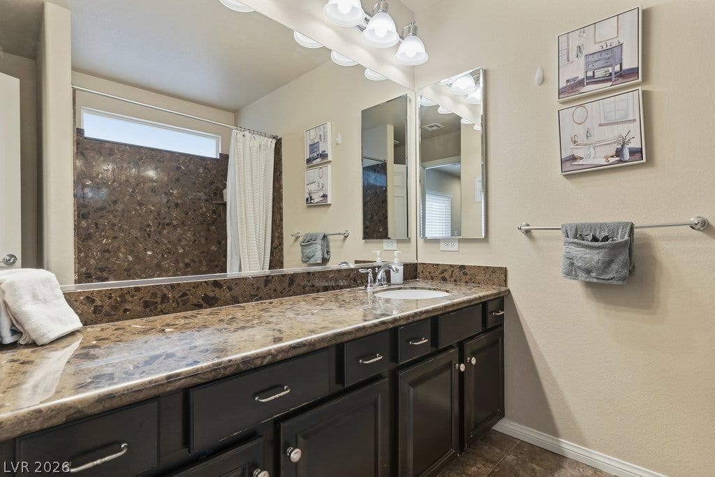 8430 Golden Amber Street, Las Vegas, NV 89139 Rich stone countertops pair with dark cabinetry to create a refined vanity space.