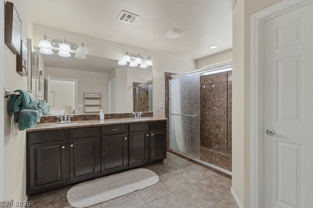 8430 Golden Amber Street, Las Vegas, NV 89139 A spacious double vanity matches the stone-patterned walk-in shower in this well-appointed bathroom.