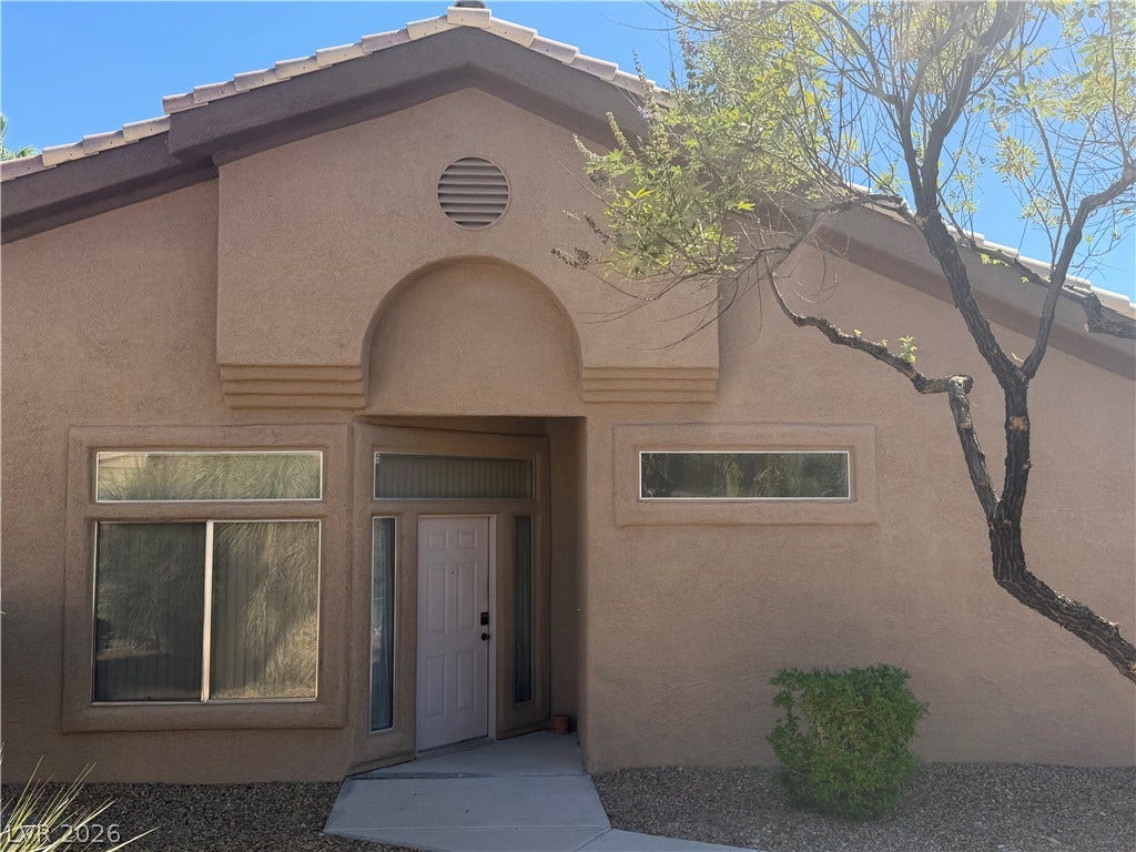 A welcoming entryway with classic stucco siding and architectural arch details greets arriving guests.