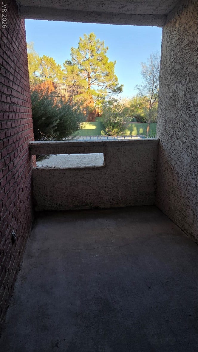 2619 Red Rock Street, #101, Las Vegas, NV 89146 An inviting covered balcony looks out toward mature trees and a sunny sky.