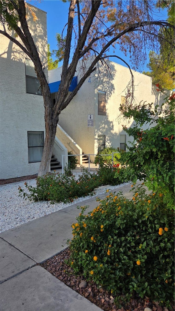 2619 Red Rock Street, #101, Las Vegas, NV 89146 A paved concrete walkway winds past lush landscaping toward the stucco exterior.