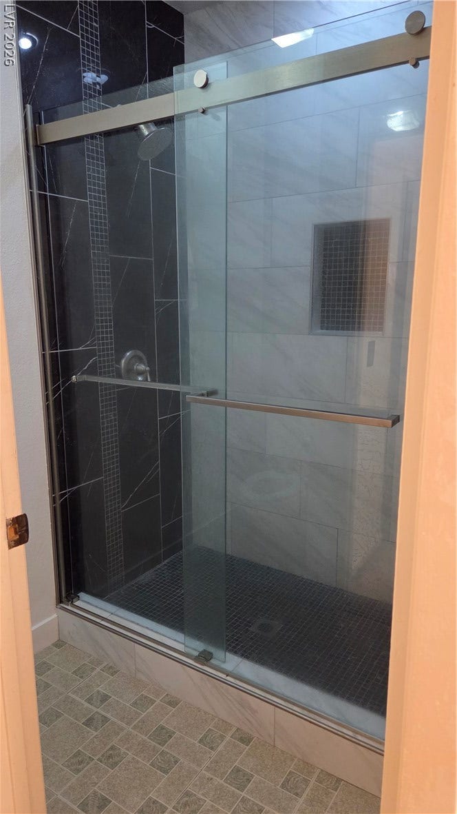2619 Red Rock Street, #101, Las Vegas, NV 89146 Contrasting tile selections accent this modern walk-in shower with sliding glass doors.