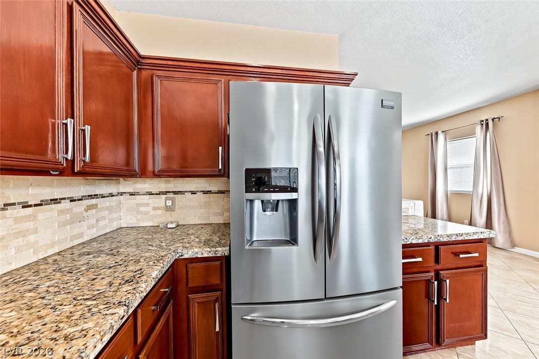 2906 Pumpkin Harvest Avenue, North Las Vegas, NV 89031 Rich wood cabinets and granite countertops define this well-appointed kitchen workspace.