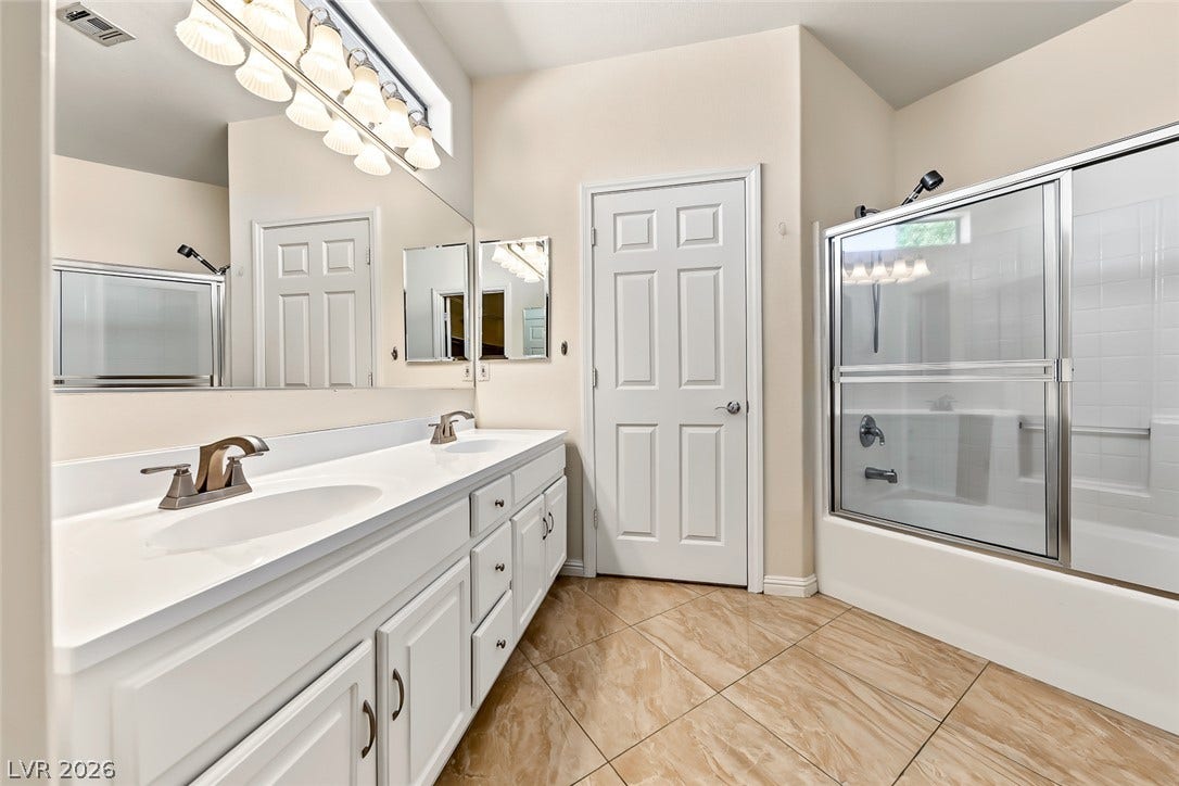 2906 Pumpkin Harvest Avenue, North Las Vegas, NV 89031 A spacious double vanity and a glass-enclosed shower highlight this classic tile-floored bathroom.