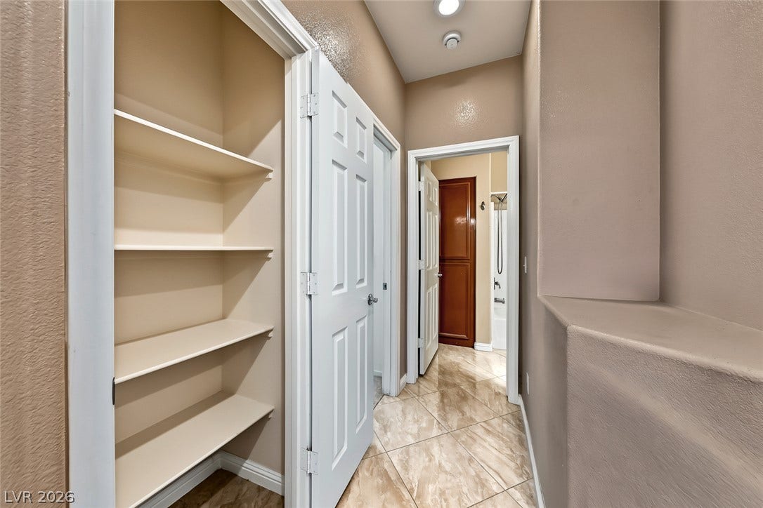2906 Pumpkin Harvest Avenue, North Las Vegas, NV 89031 An organized hallway closet features built-in shelving alongside polished tile floors and recessed lighting.