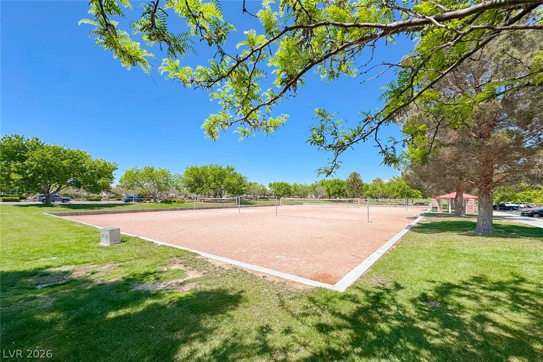 2906 Pumpkin Harvest Avenue, North Las Vegas, NV 89031 Lush green lawns and mature trees frame the community sand volleyball courts under clear blue skies.