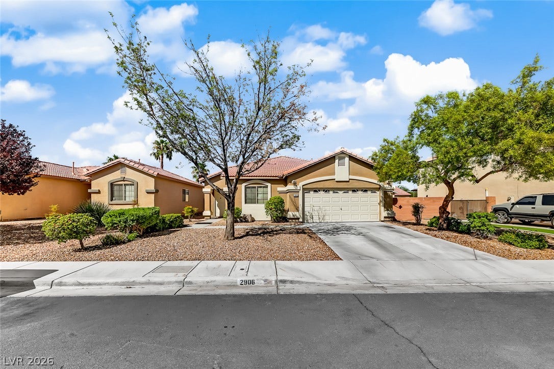 2906 Pumpkin Harvest Avenue, North Las Vegas, NV 89031 Desert landscaping and a concrete driveway lead to this classic tile-roofed home with an attached garage.