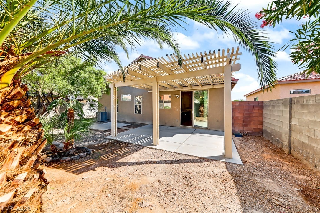 2906 Pumpkin Harvest Avenue, North Las Vegas, NV 89031 An inviting backyard patio features a spacious concrete pad covered by a classic wooden pergola.