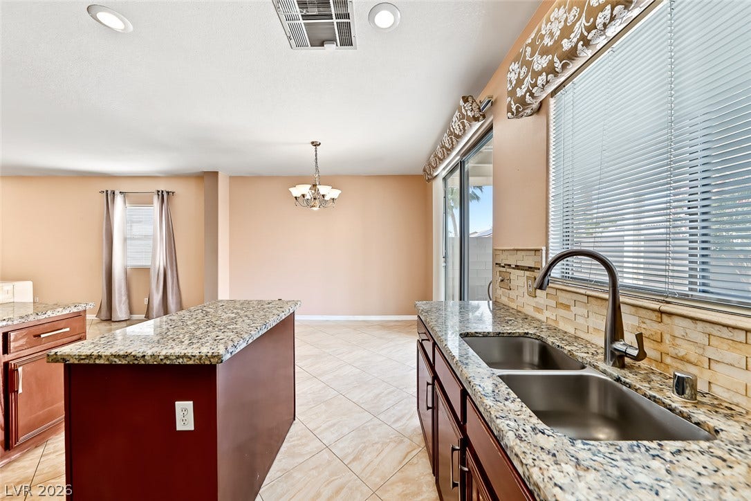 2906 Pumpkin Harvest Avenue, North Las Vegas, NV 89031 Polished granite countertops complement the tile flooring in an open-concept kitchen.