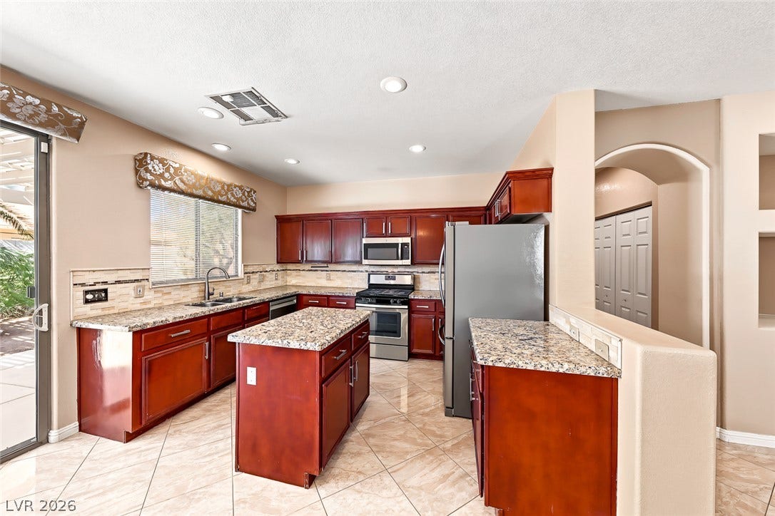 2906 Pumpkin Harvest Avenue, North Las Vegas, NV 89031 Granite countertops and warm wood cabinetry define this functional kitchen space with tile flooring.