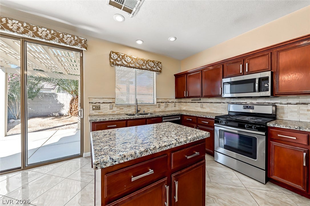 2906 Pumpkin Harvest Avenue, North Las Vegas, NV 89031 Gleaming stone countertops and rich wooden cabinetry anchor this well-appointed kitchen.
